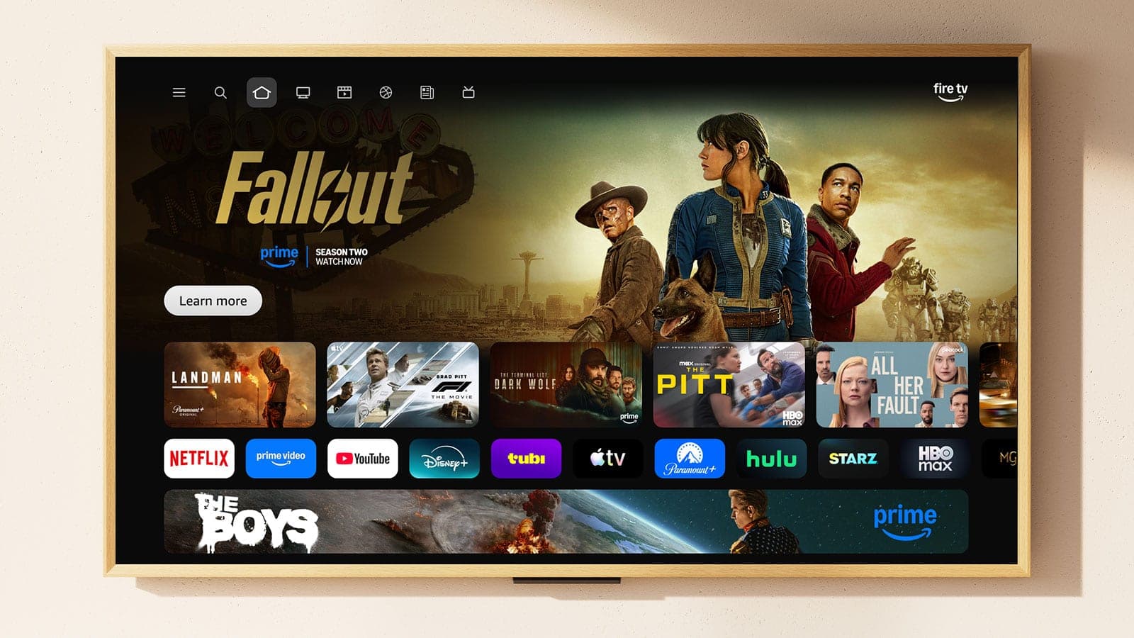 The Fire TV home screen on a wall-mounted TV, showing the Fallout show and a row of streaming app icons