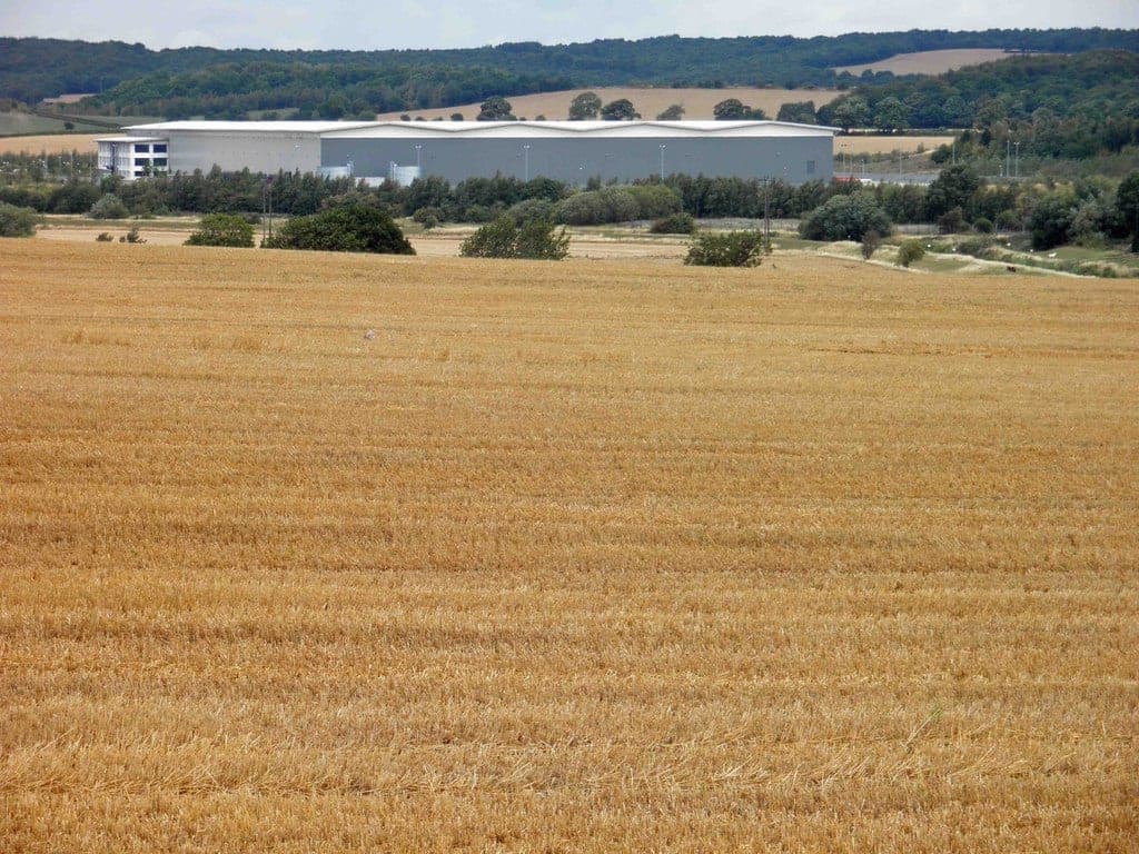 An ASOS warehouse seen across a harvested wheat field from Darfield, England