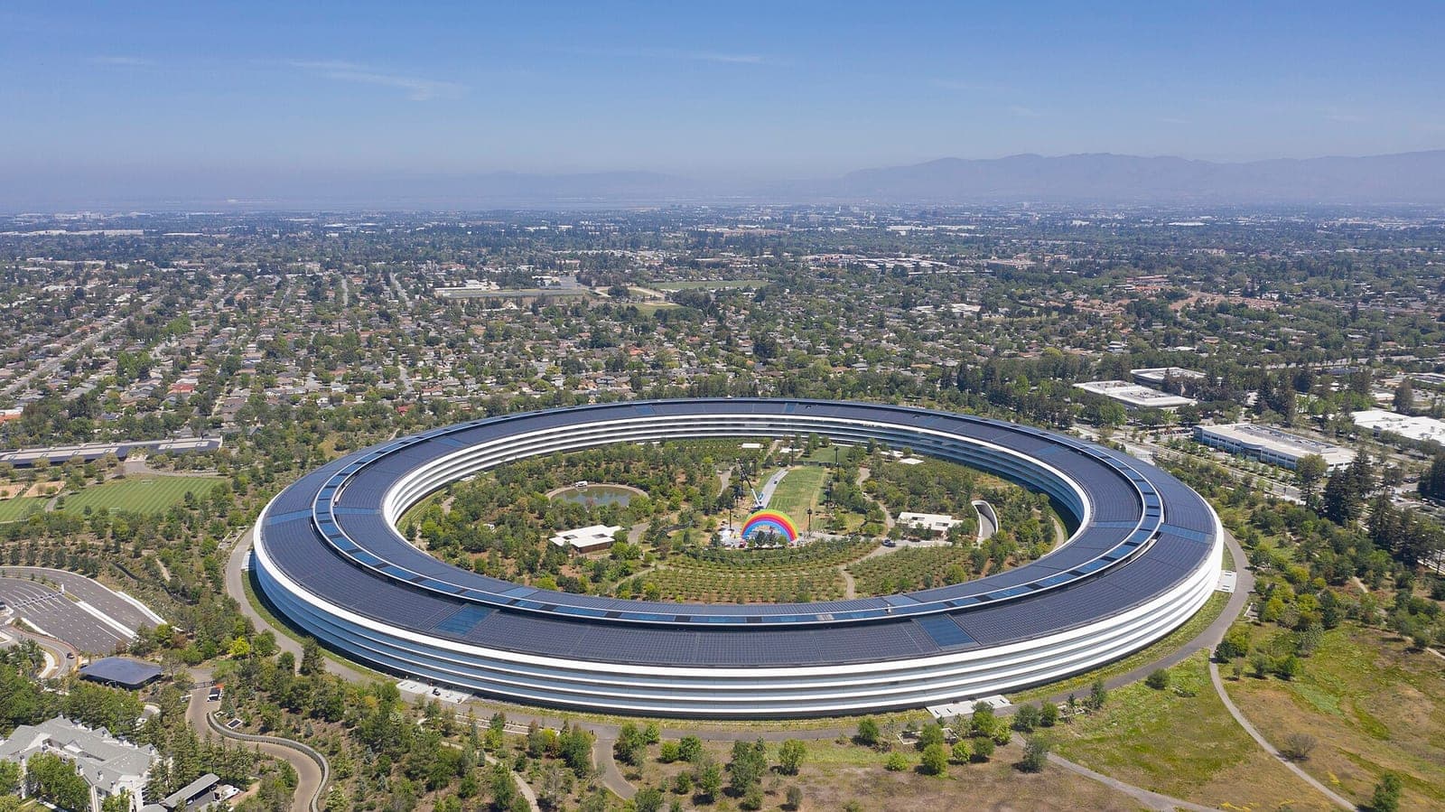 Aerial view of Apple Park in Cupertino, the ring-shaped Apple headquarters surrounded by trees and suburban streets