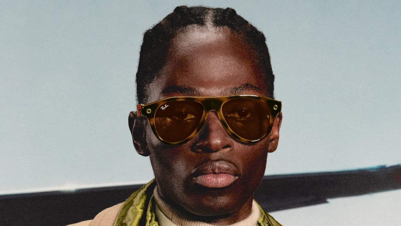 A close-up portrait of a person wearing tortoiseshell Ray-Ban Meta smart glasses with amber lenses