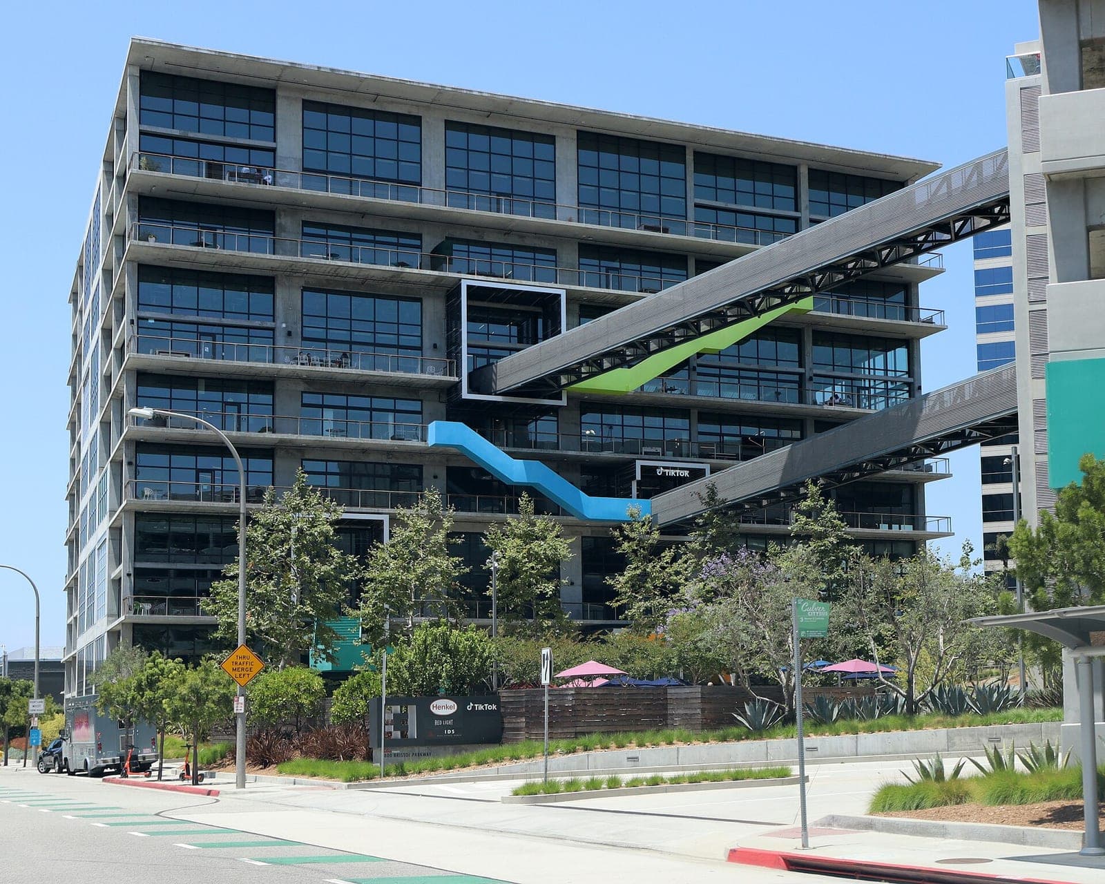 TikTok's office building at 5800 Bristol Parkway in Culver City, California, with dark windows, balconies, and blue and green external stairways under a clear sky