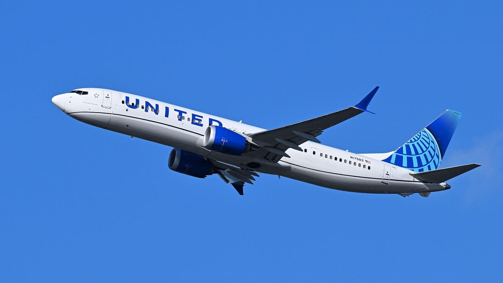 A United Airlines Boeing 737 MAX 9 in white and blue livery climbing against a clear blue sky