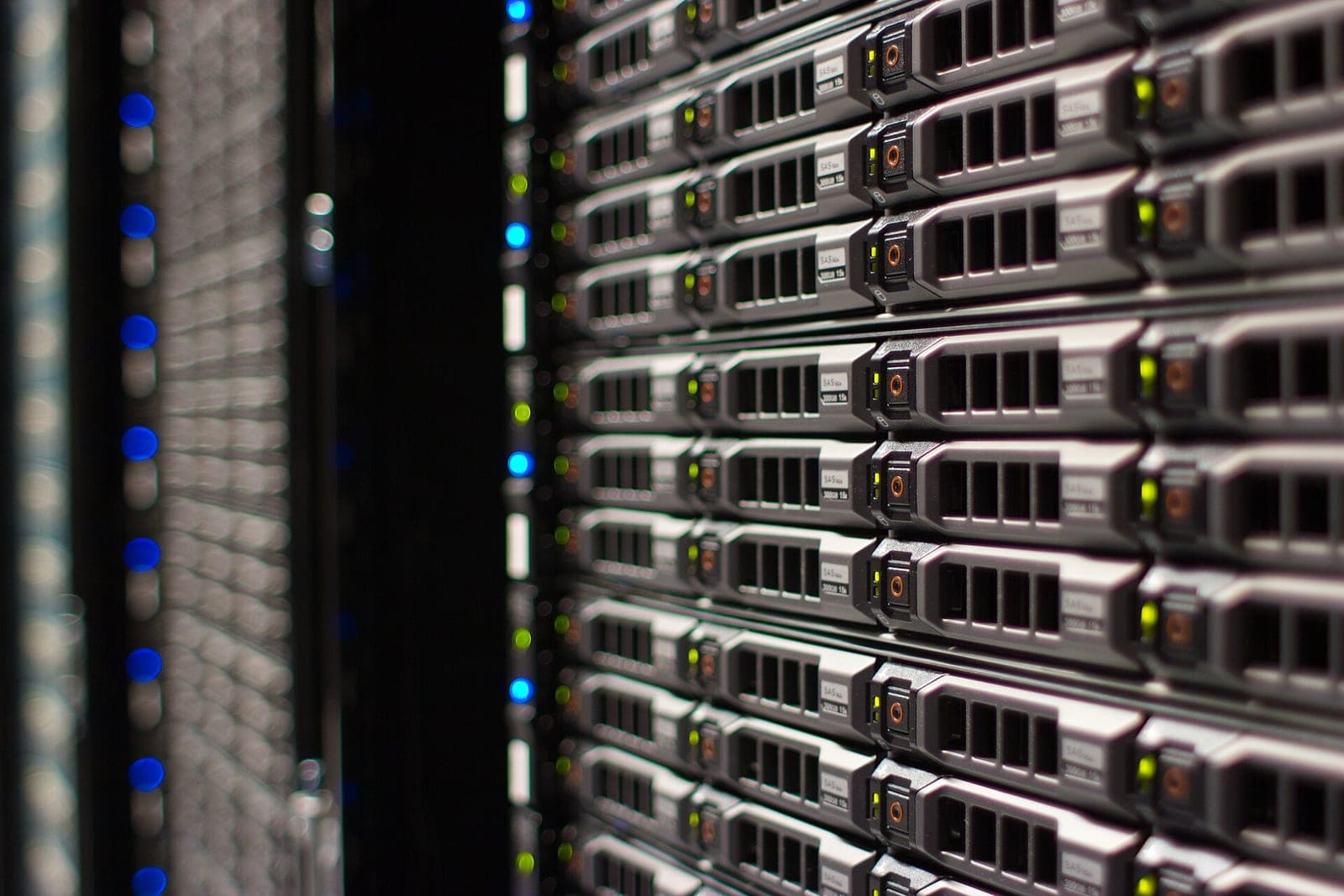 A close-up of rows of Wikimedia Foundation servers in a rack, with blue and green status lights glowing in a dark data center