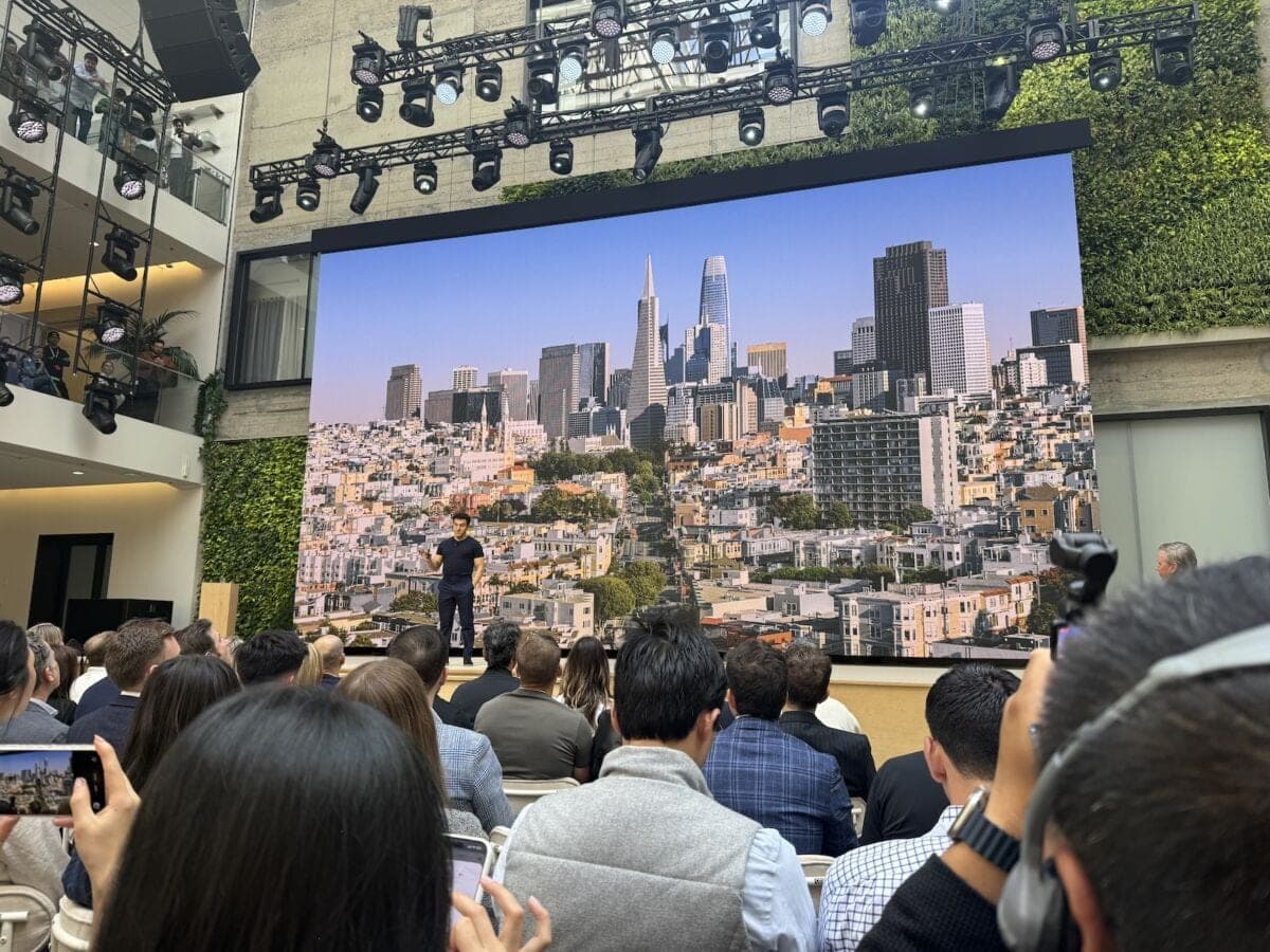 A presenter on stage in front of a large screen showing a San Francisco skyline during an Airbnb event