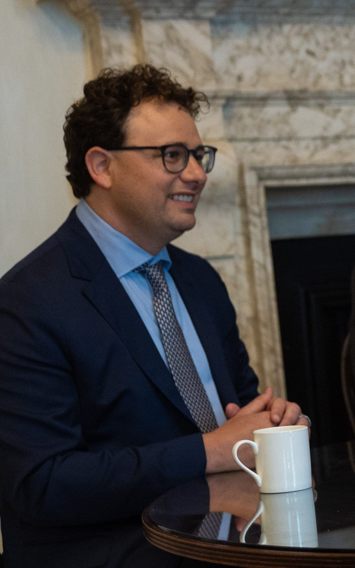 Dario Amodei smiling in a suit and tie at a formal meeting setting