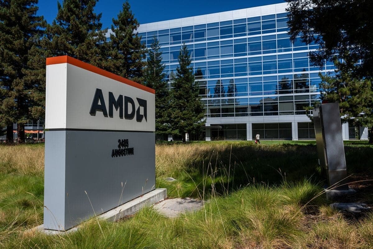 AMD's corporate headquarters sign outside its glass office building in Santa Clara, California, surrounded by trees and landscaped grass.