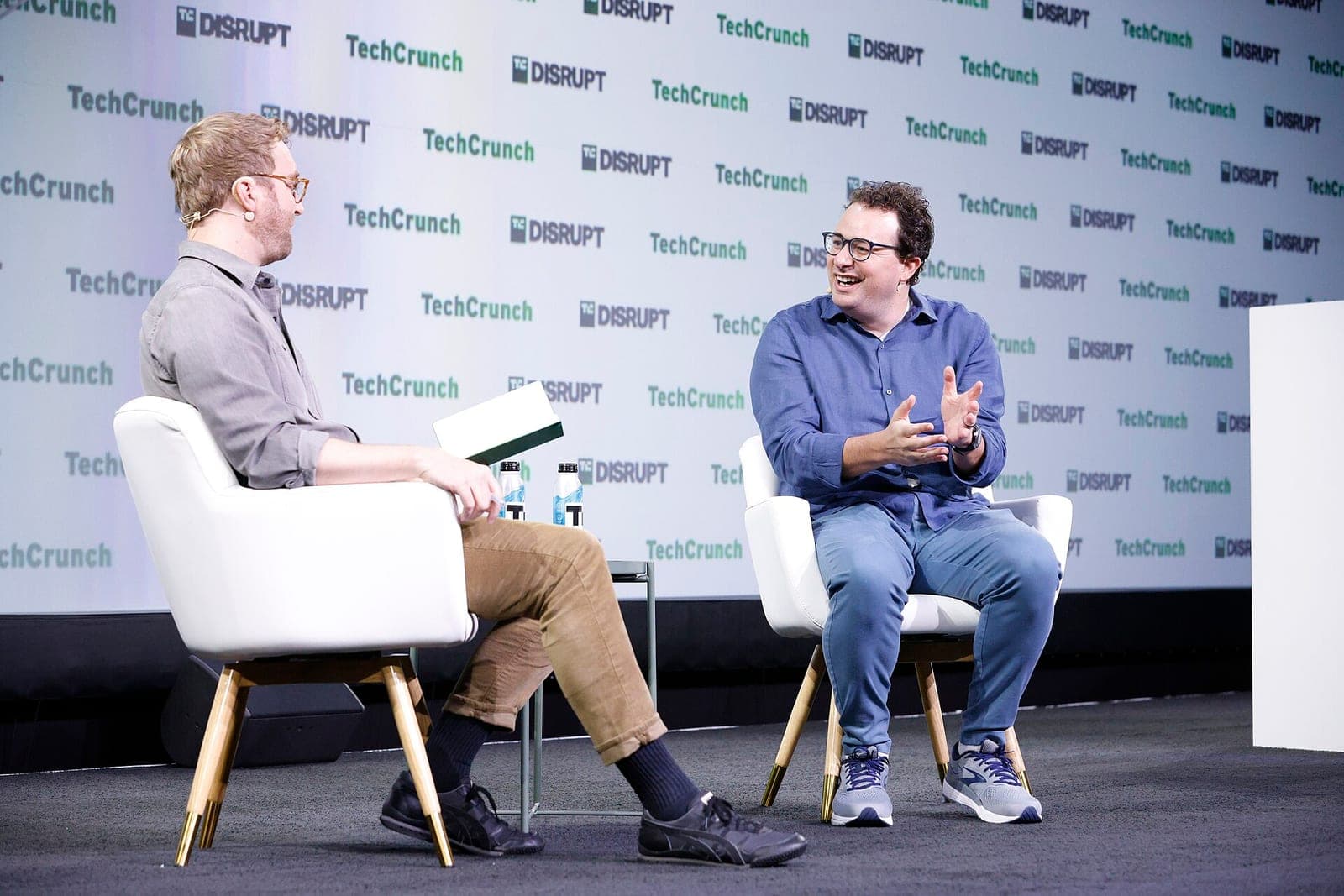 Anthropic CEO Dario Amodei, in a blue shirt and glasses, talking on stage with an interviewer at TechCrunch Disrupt 2023