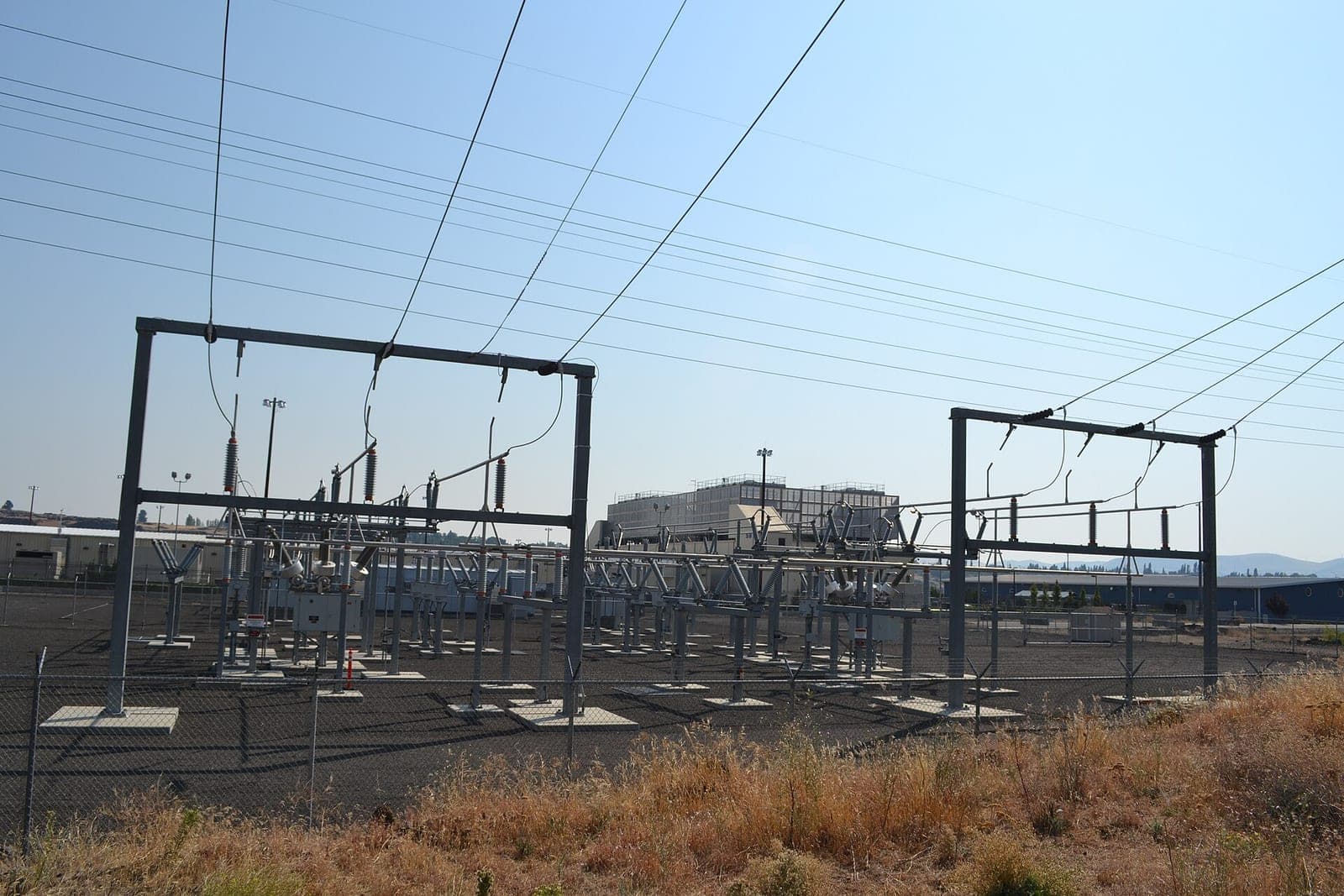 An electrical substation with transformers and power lines next to a large data center building