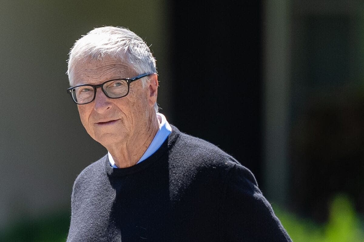 Portrait of Bill Gates wearing glasses and a dark sweater, outdoors