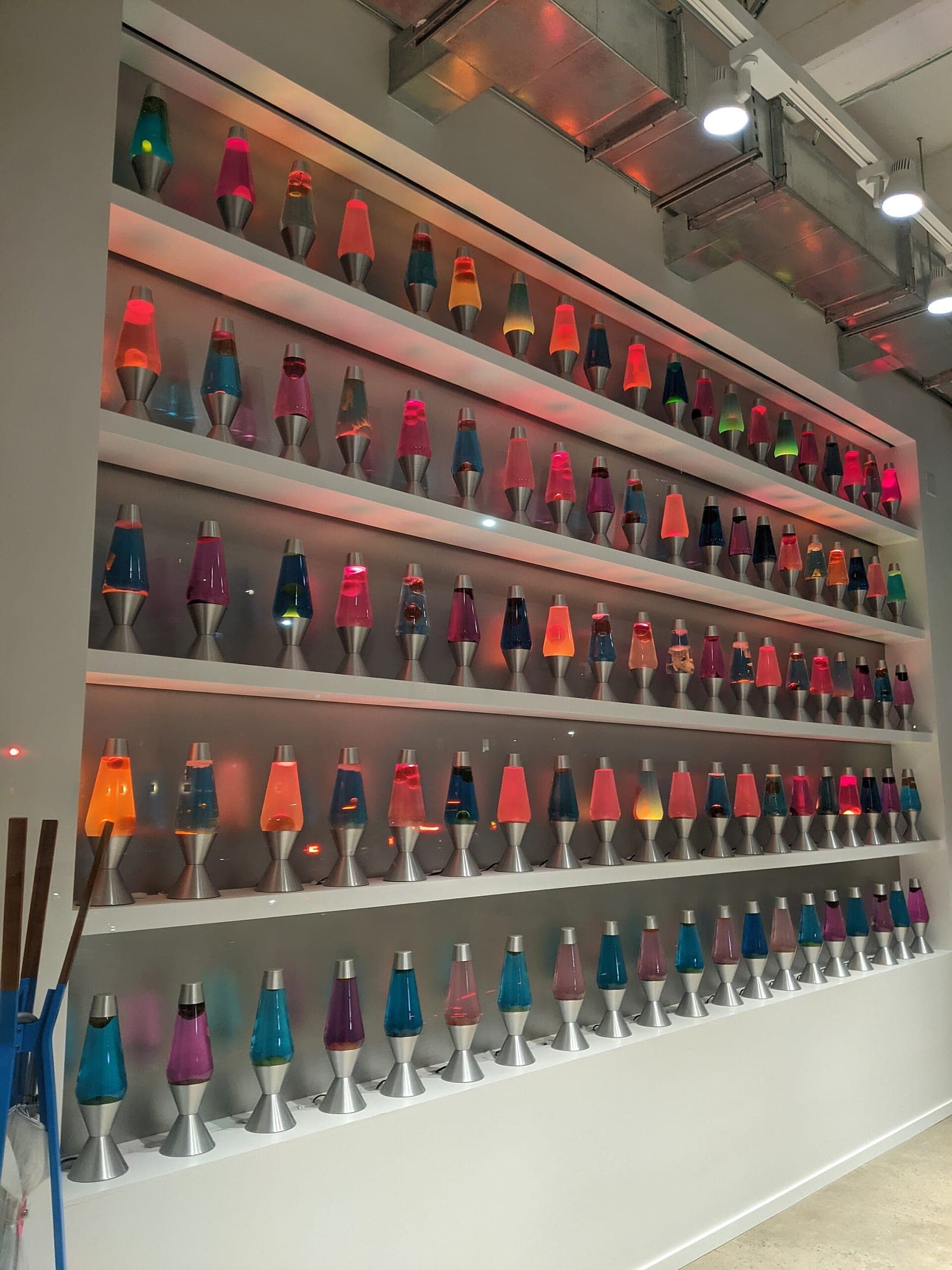 Rows of colorful glowing lava lamps on white shelves at a Cloudflare office