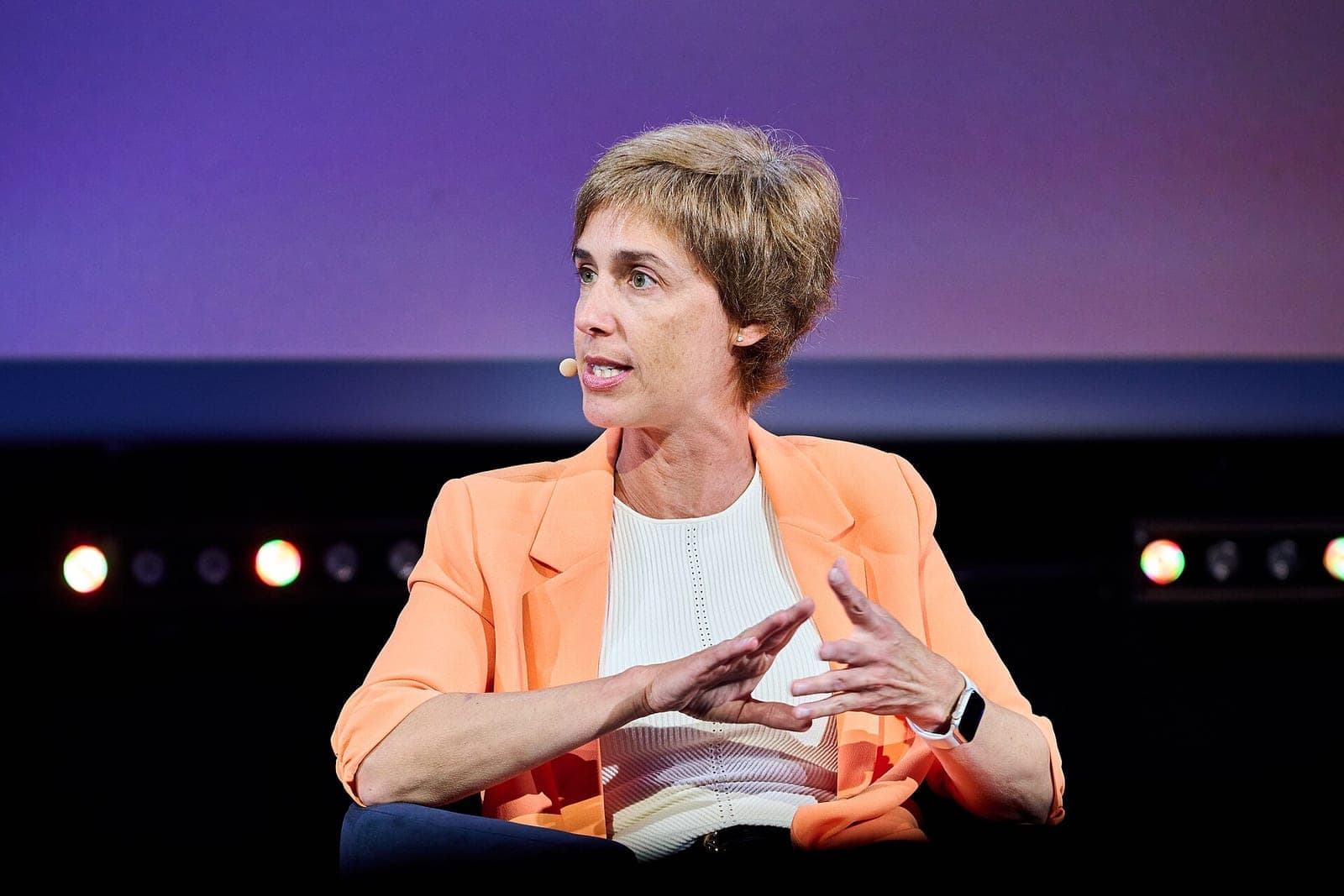 Cohere chief AI officer Joëlle Pineau, in an orange blazer and wearing a headset microphone, speaking on a panel at the ALL IN AI conference in Montreal in September 2025