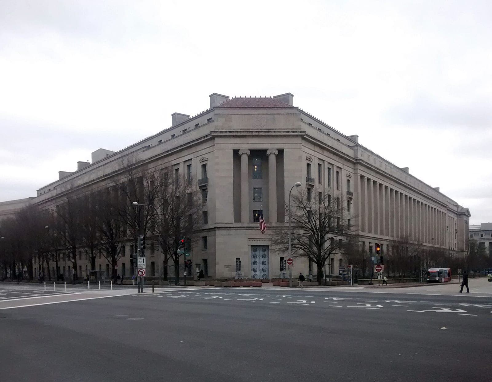 The Robert F. Kennedy Department of Justice Building in Washington, DC, a large stone building on a street corner under a gray sky.