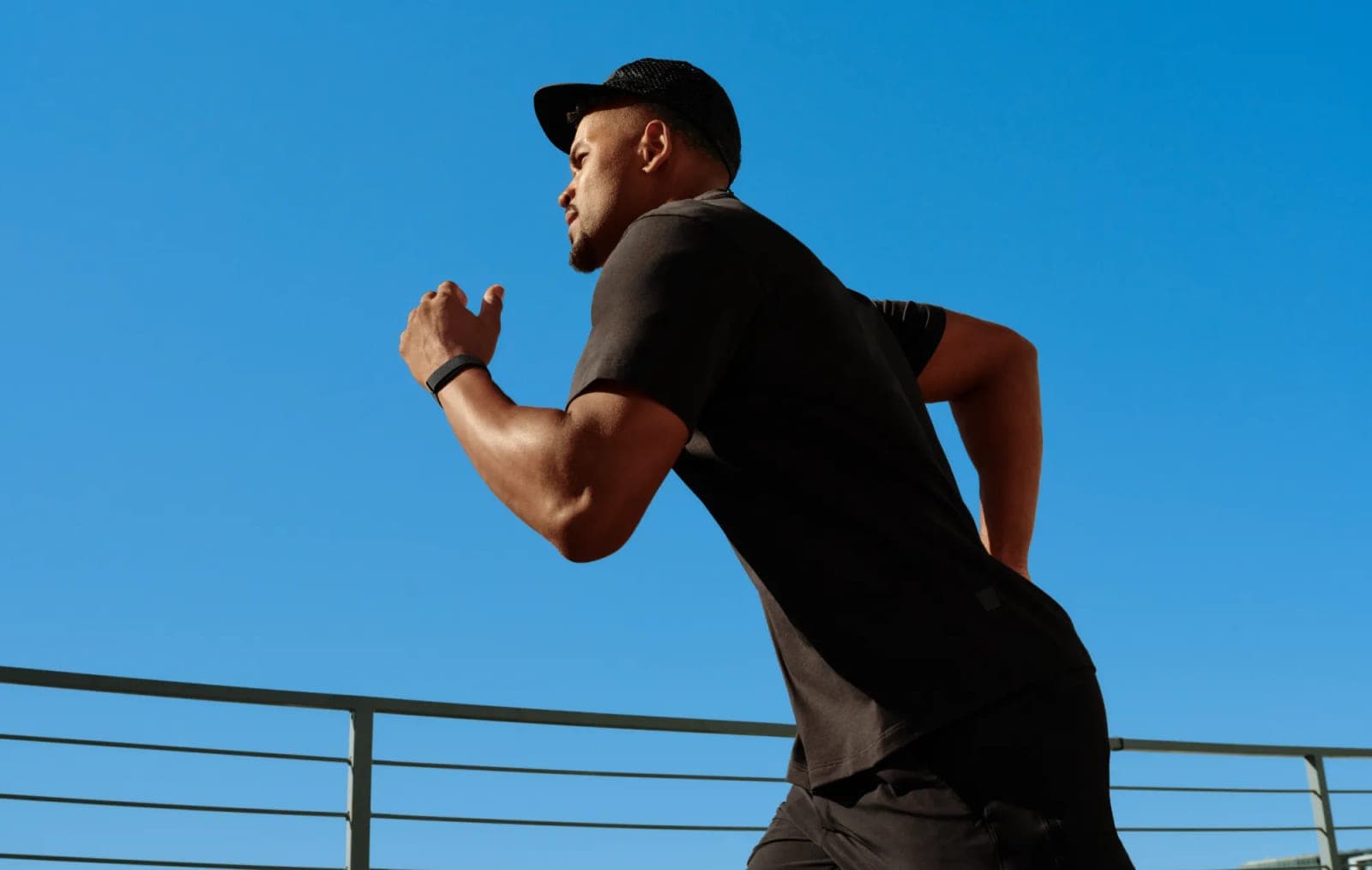 A man running outdoors wearing the Fitbit Air band on his wrist
