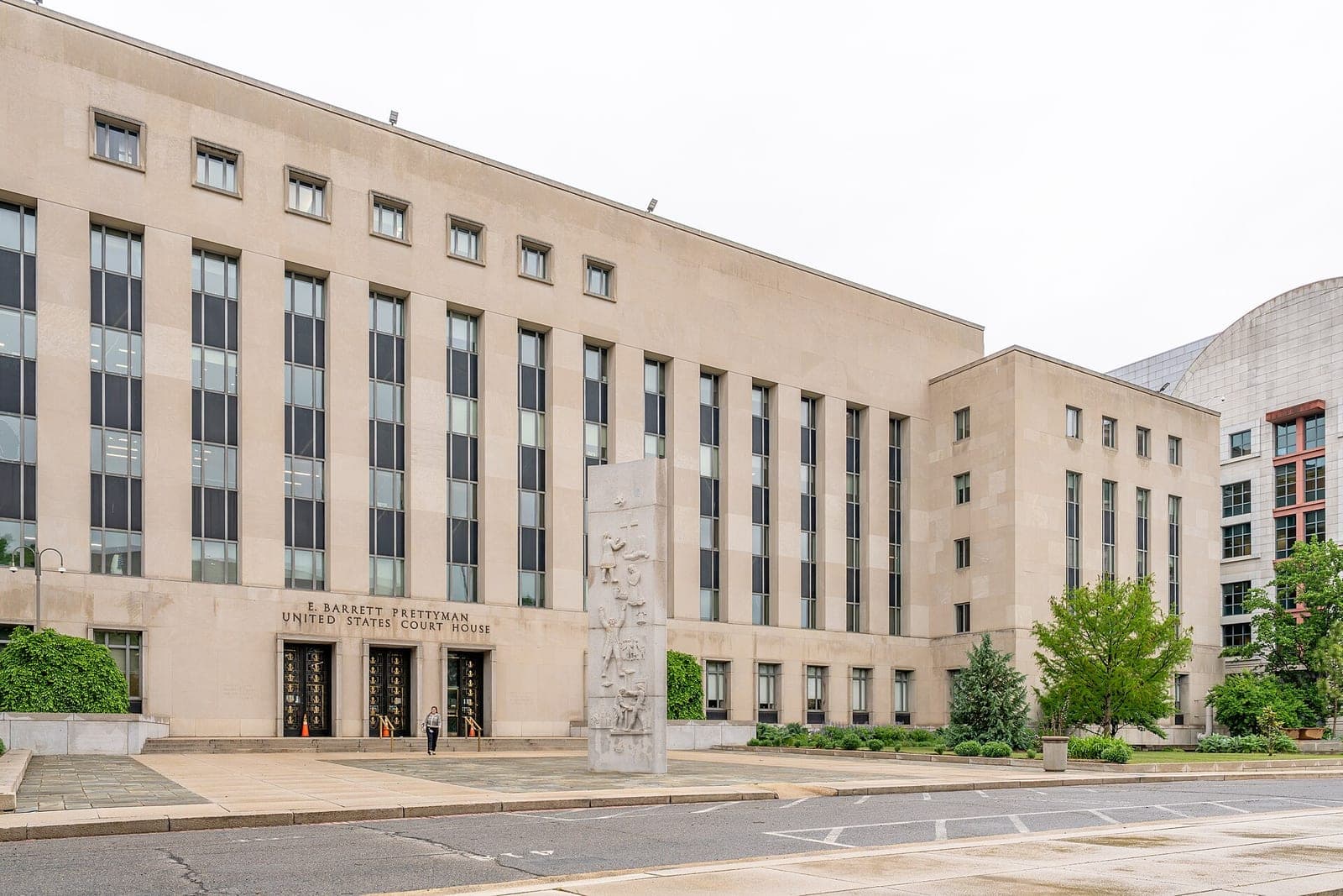The stone facade of the E. Barrett Prettyman United States Court House in Washington, D.C., with a carved monument in front