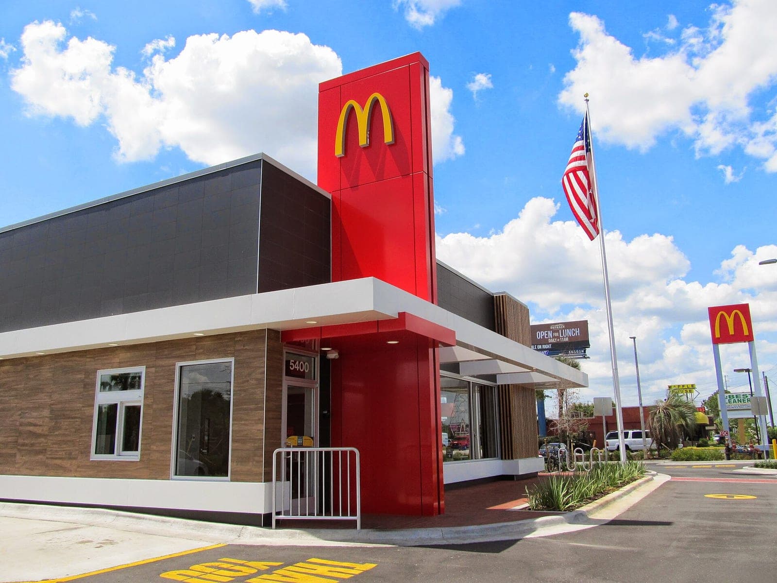 The exterior of a McDonald's restaurant with a large illuminated Golden Arches sign and American flag