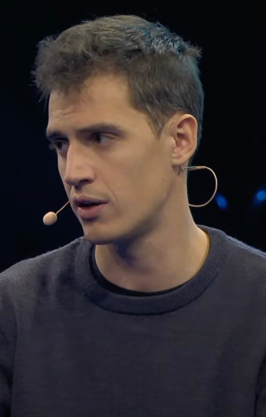Arthur Mensch, co-founder and CEO of Mistral AI, speaking with a headset microphone against a dark stage background