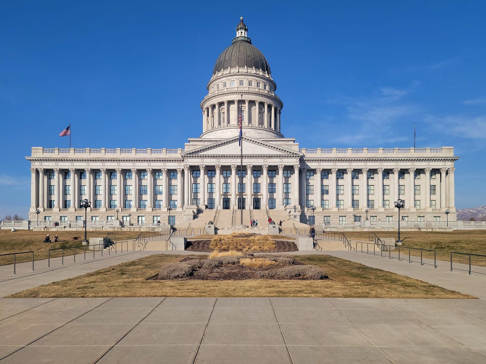 The Utah State Capitol in Salt Lake City, a white neoclassical building with a grey dome and columns, under a clear blue sky