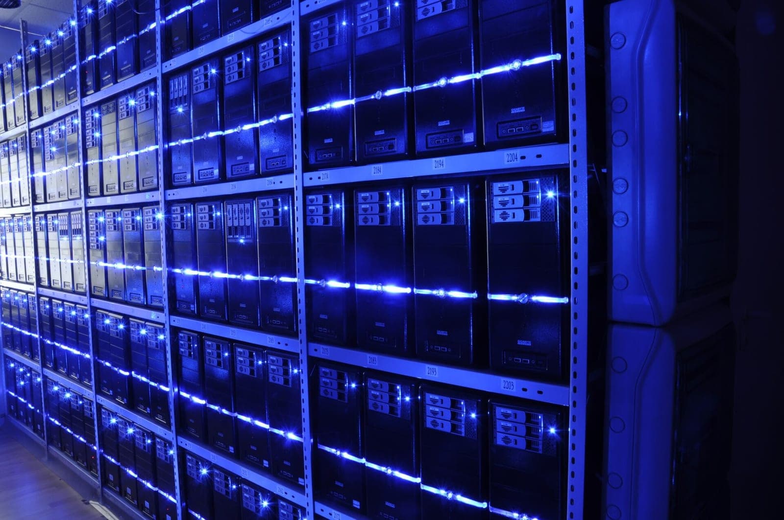 Rows of server racks glowing with blue indicator lights in a dark data center