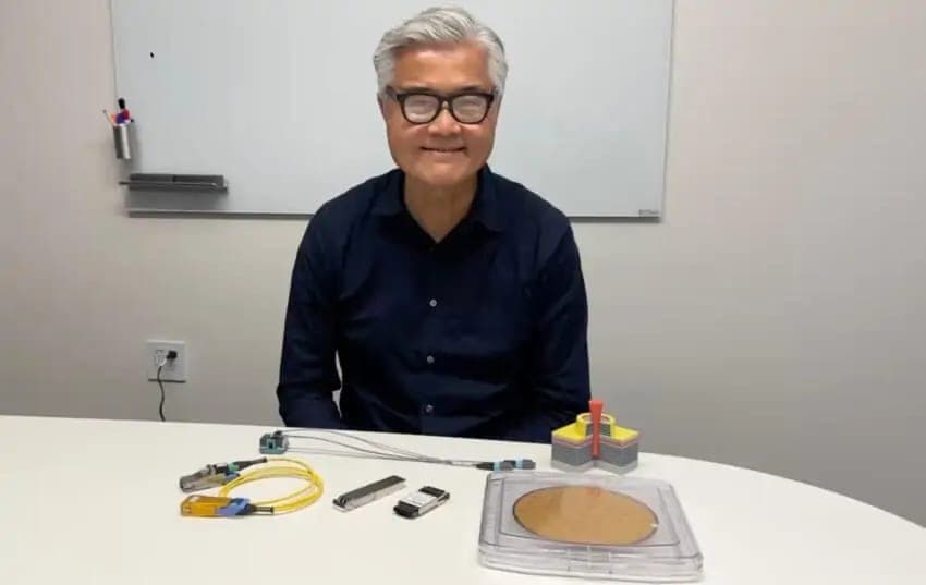 PicoJool CEO Al Yuen sitting at a table with the company's optical connector cables and VCSEL wafer products