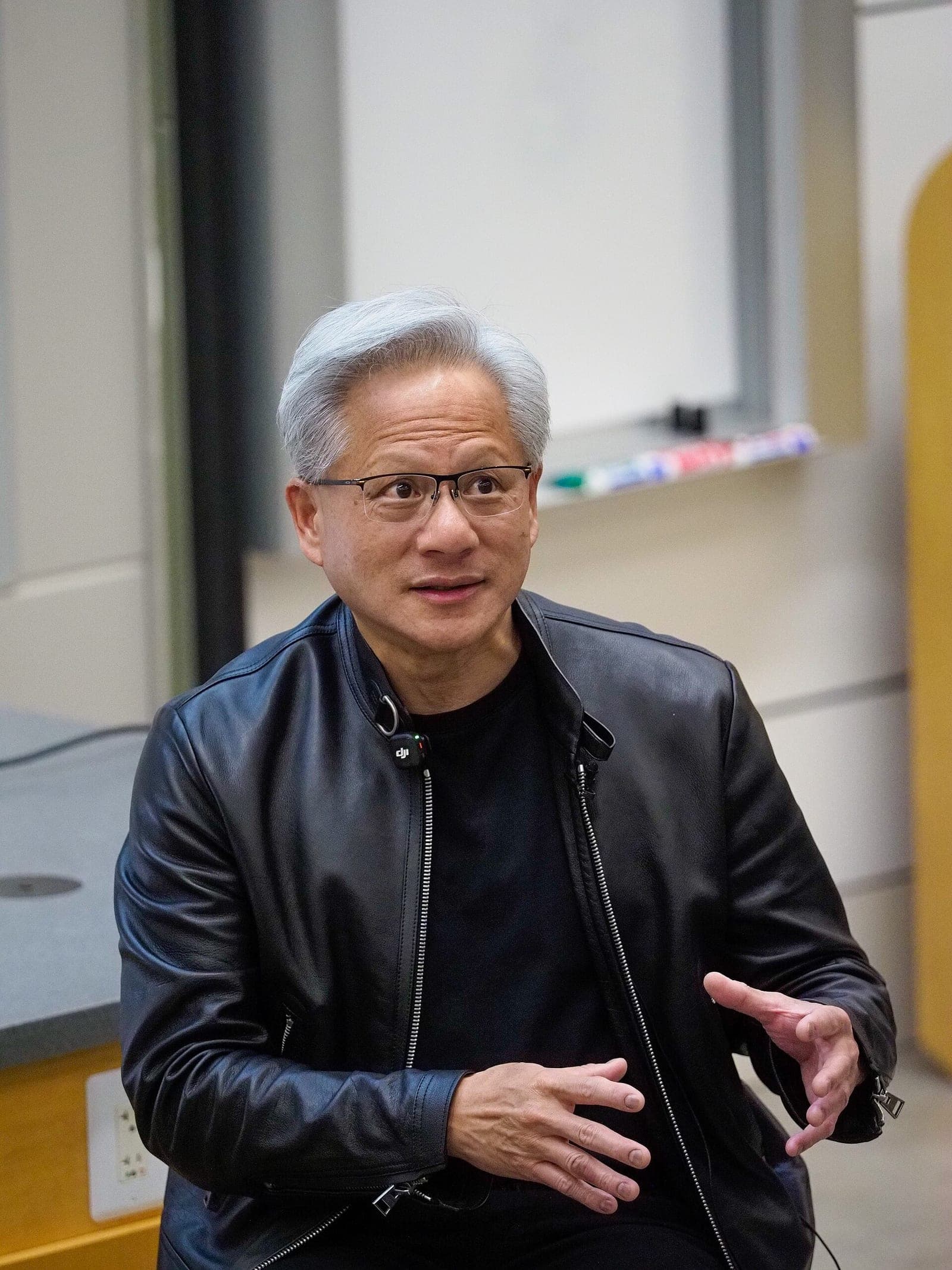Nvidia CEO Jensen Huang, wearing a black leather jacket, speaking and gesturing with his hands.